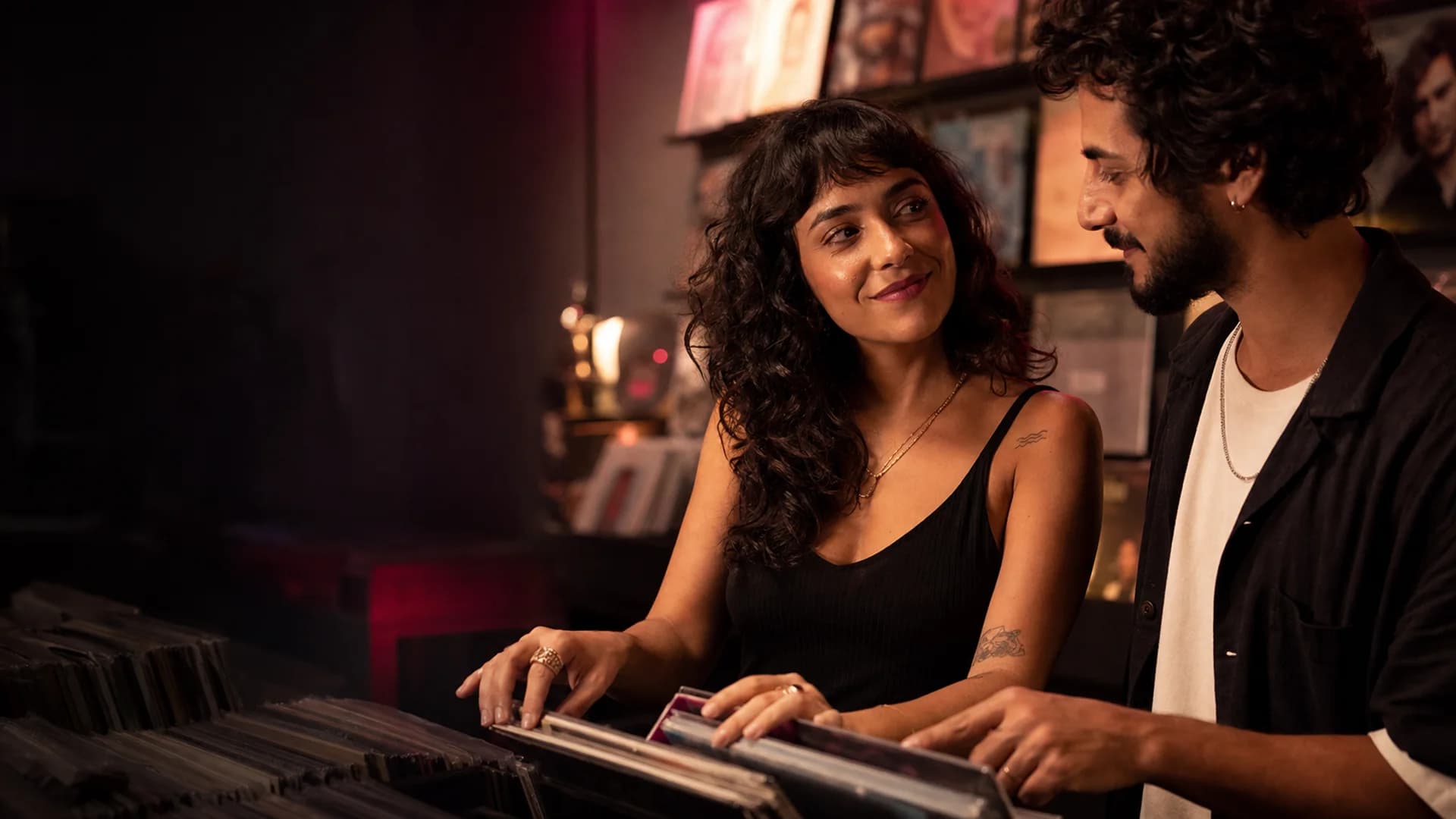 Mulher e homem trocam olhares enquanto escolhem discos juntos